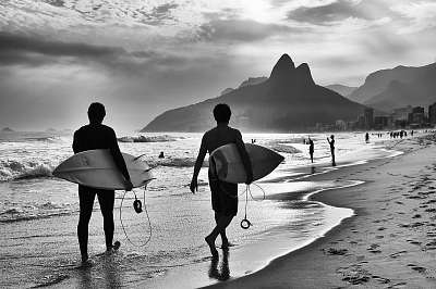 Scenic black and white view of Rio de Janeiro, Brazil with Brazilian surfers walking along the shore of Ipanema Beach (bögre) - vászonkép, falikép otthonra és irodába