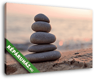 Stacked stones on the beach at sunset - vászonkép 3D látványterv