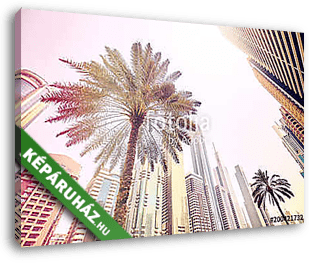 Palm trees in front of modern skyscrapers in Dubai, color toned  - vászonkép 3D látványterv