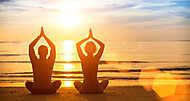 Fiatal pár jógázik a tengerparton naplementében vászonkép, poszter vagy falikép