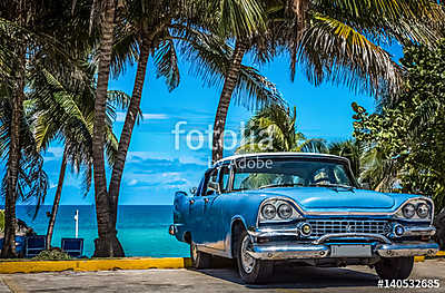 Kék amerikai vintage autó parkolt a strandon pálmafák alatt V-be (keretezett kép) - vászonkép, falikép otthonra és irodába