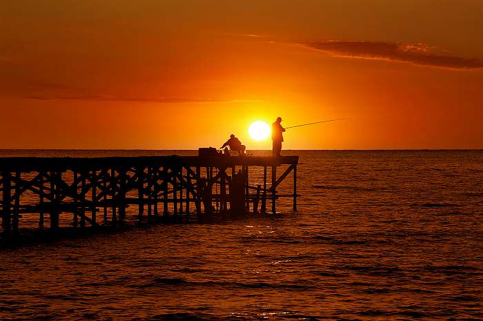 két halász a naplementében a tengeren lévő hídon, Premium Kollekció